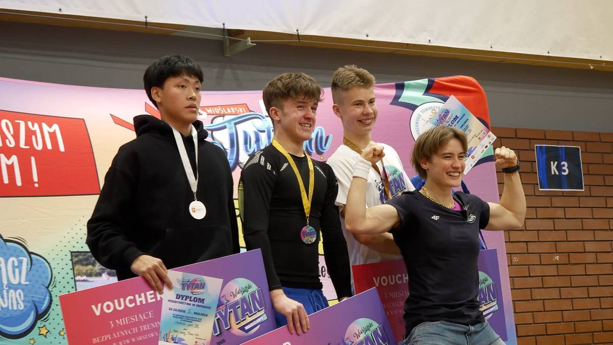 Czterech młodych ludzi stoi na podium, trzymając nagrody i medale.