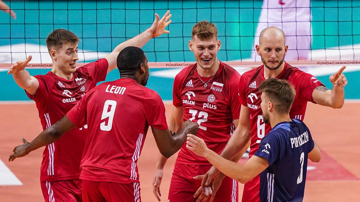 Grupa siatkarzy w czerwonych koszulkach świętuje zwycięstwo na boisku.