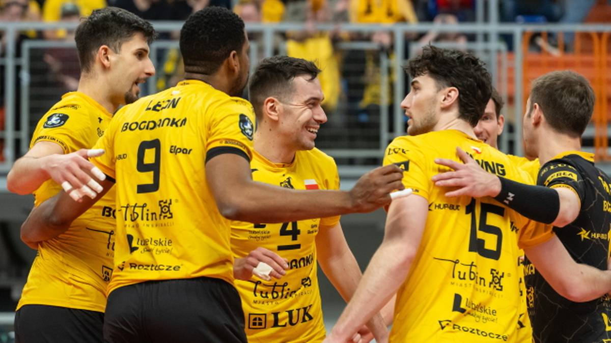 Pięciu siatkarzy w ż&oacute;łtych koszulkach rozmawia na boisku podczas meczu siatk&oacute;wki.