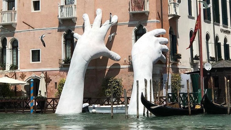 Ręce wynurzające się z wody w Wenecji. Mają zwrócić uwagę na globalne ocieplenie