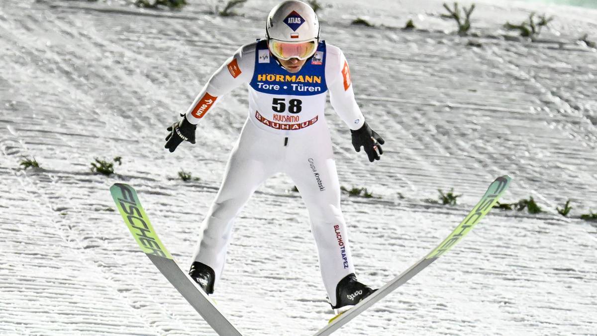 Skoczek narciarski w białym kombinezonie z numerem 58.