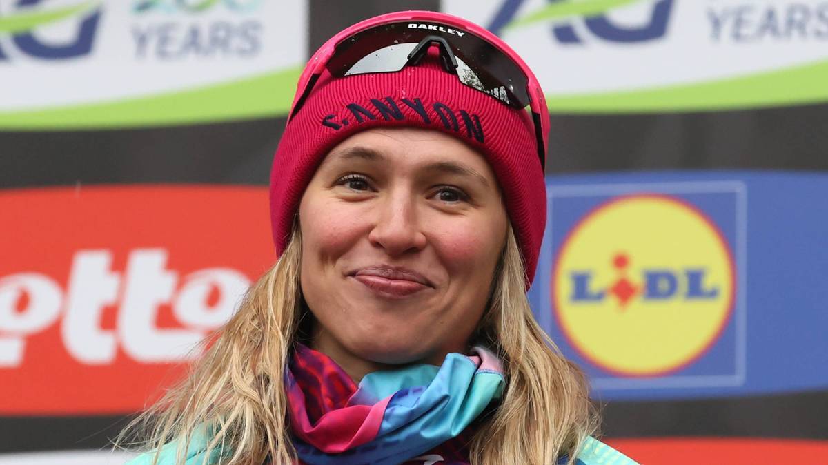 Uśmiechnięta twarz Katarzyny Niewiadomej, polskiej kolarki, podczas ceremonii medalowej. Nosi r&oacute;żową czapkę z napisem "Canyon" i okulary przeciwsłoneczne na czubku głowy.