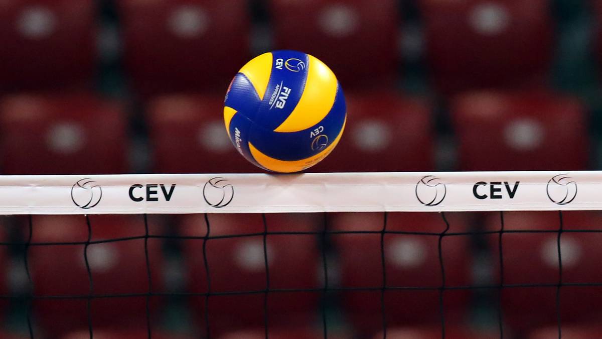 Piłka do siatk&oacute;wki leżąca na siatce z widocznymi logotypami CEV w tle czerwonych trybun.