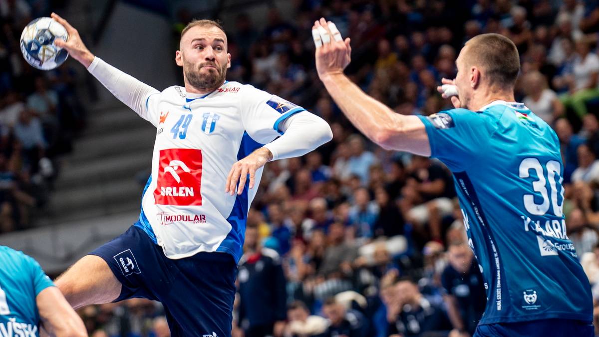 Dwóch zawodników piłki ręcznej podczas meczu. Jeden z nich w białej koszulce z numerem 49 próbuje rzucić piłkę do bramki, podczas gdy drugi zawodnik w niebieskiej koszulce z numerem 30 próbuje go zablokować.