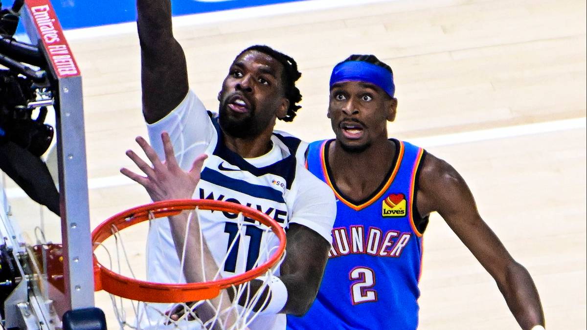 Dwóch koszykarzy NBA grających w meczu. Jeden zawodnik w białej koszulce z numerem 77 próbuje rzucić do kosza, podczas gdy drugi zawodnik w niebieskiej koszulce z numerem 2 stara się go zablokować.