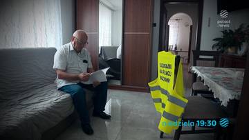 Starszy mężczyzna w okularach siedzi na kanapie, czyta dokumenty. Obok stoi żółta kamizelka odblaskowa.