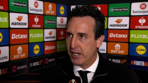 Unai Emery, trener piłkarski, stoi przed ścianą z logo sponsor&oacute;w, m&oacute;wiąc do kamery.