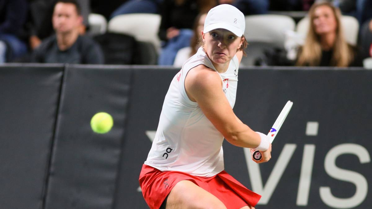 Iga Świątek podczas meczu tenisowego, przygotowująca się do uderzenia piłki.