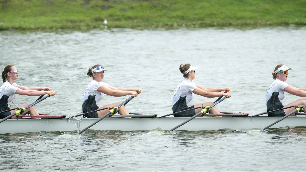 Cztery młode kobiety w łodzi wioślarskiej w trakcie zawodów.