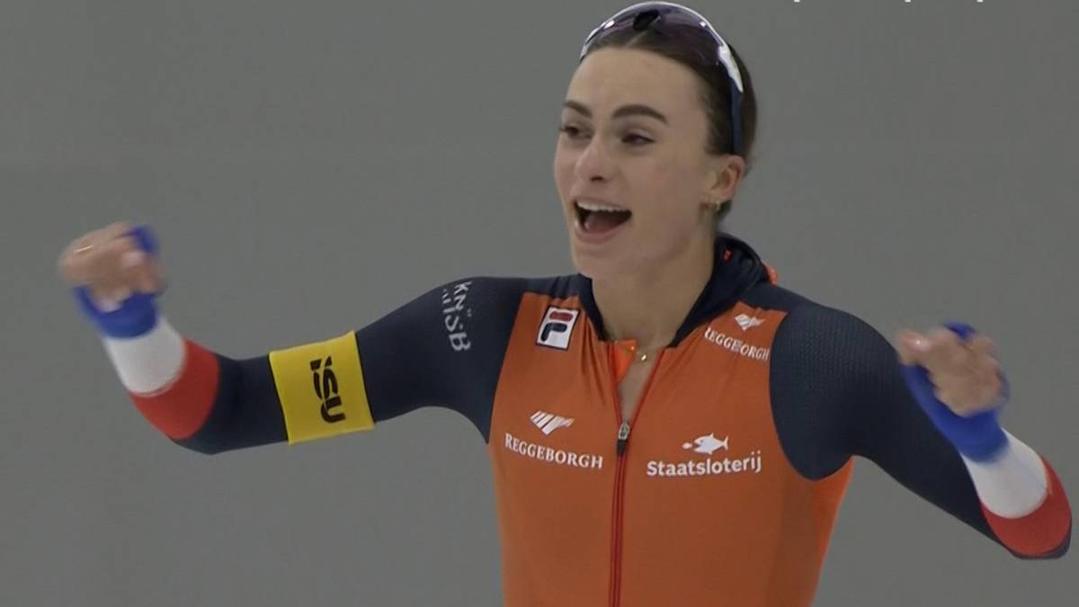 Łyżwiarka szybka w pomarańczowo-szarym stroju cieszy się ze zwycięstwa, podnosząc pięści do góry.