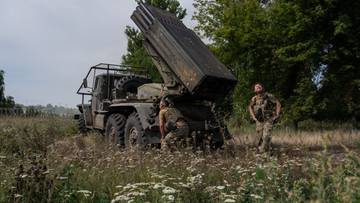 Wojskowa wyrzutnia rakietowa na ciężar&oacute;wce ukryta w zaroślach z dwoma żołnierzami w pobliżu.
