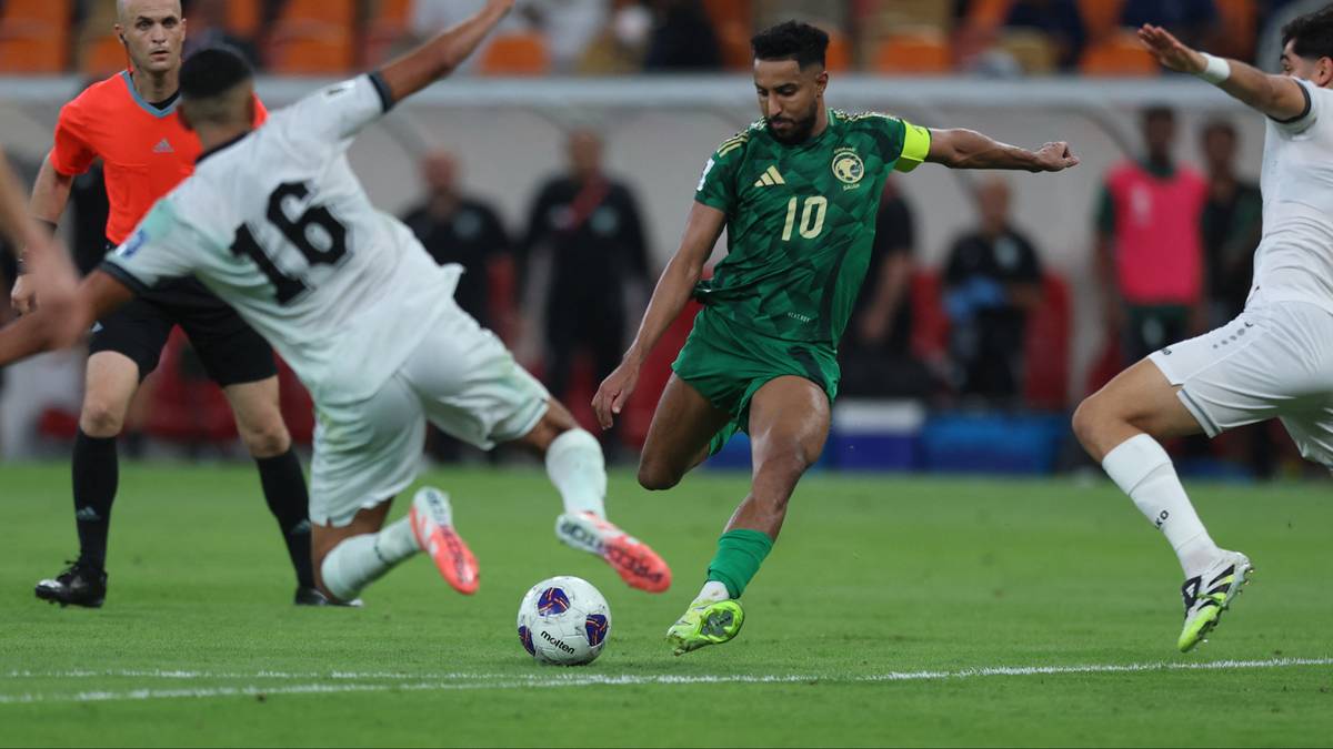 Piłkarz w zielonej koszulce z numerem 10 drybluje, podczas gdy zawodnik w białej koszulce z numerem 16 próbuje go zatrzymać. W tle widać innych zawodników i kibiców.