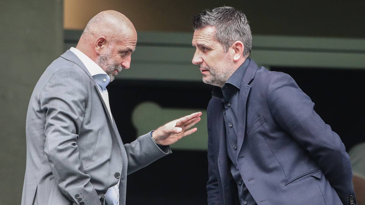 Dwóch mężczyzn w garniturach rozmawia ze sobą.