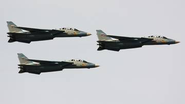 Trzy myśliwce wojskowe lecące w formacji na tle jasnego nieba.