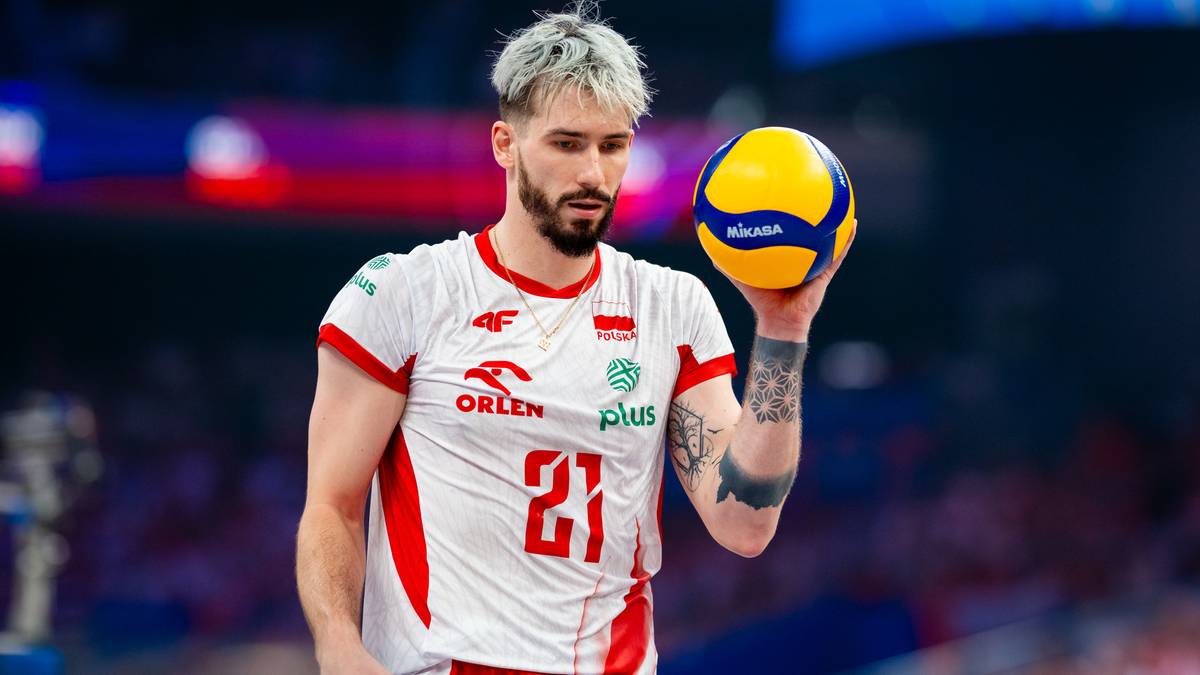 Siatkarz Tomasz Fornal w białej koszulce z numerem 21 i żółto-niebieską piłką w dłoni.