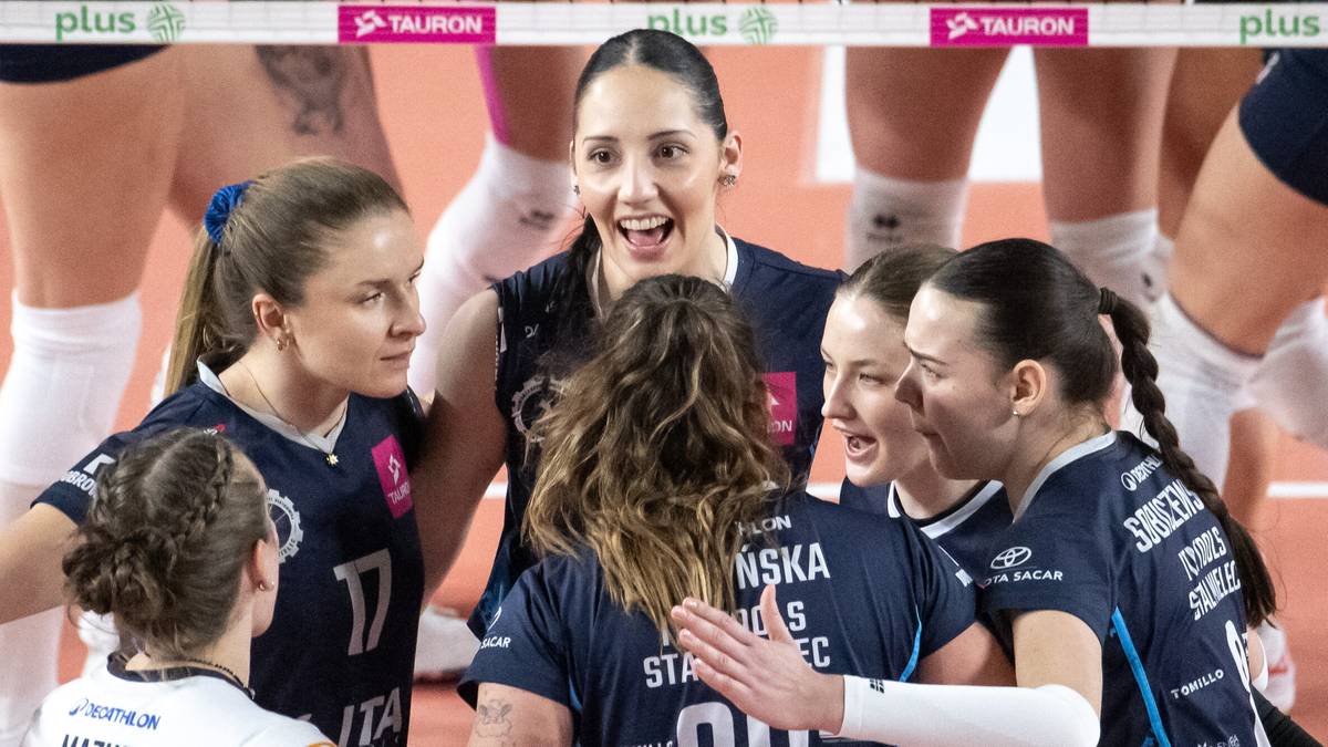 Grupa siatkarek celebrująca zwycięstwo na boisku siatkarskim.