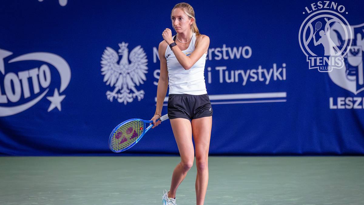 Tenisistka trzyma rakietę w ręku, stojąc na korcie tenisowym.