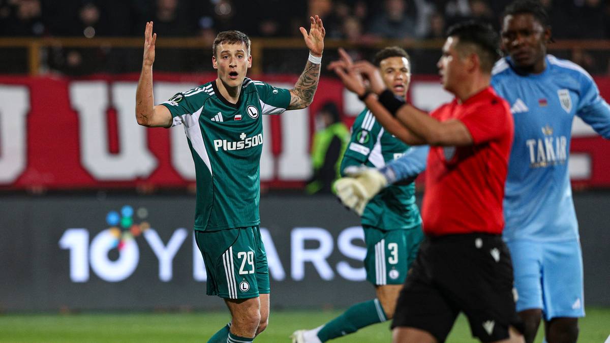 Piłkarz w zielonej koszulce z numerem 25 na plecach gestykuluje rękami, protestując wobec decyzji sędziego. W tle widać innych piłkarzy oraz fragment trybun.