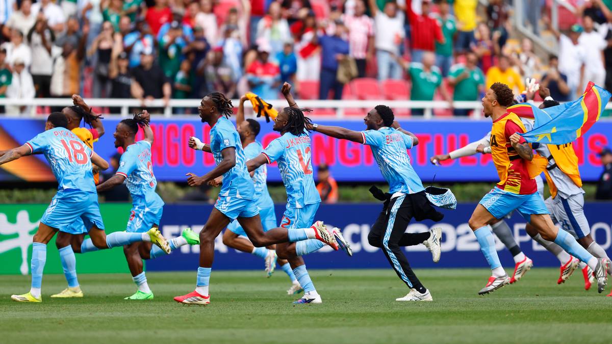 Piłkarze w jasnoniebieskich strojach biegają po boisku, ciesząc się ze zwycięstwa. W tle widoczni są kibice na trybunach.