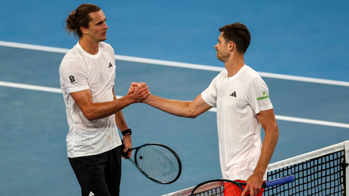 Dw&oacute;ch tenisist&oacute;w podaje sobie ręce przy siatce po zakończonym meczu tenisowym.