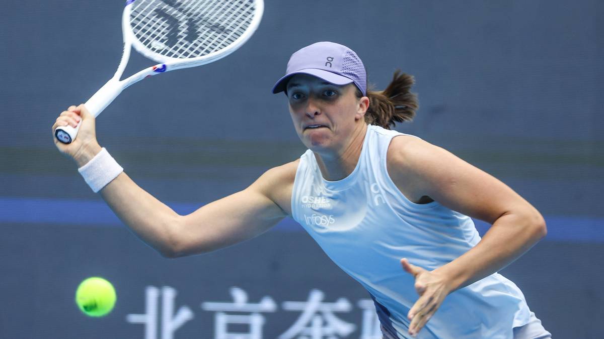 Iga Świątek podczas meczu tenisowego, wykonuje zamaszyste uderzenie rakietą w piłkę.