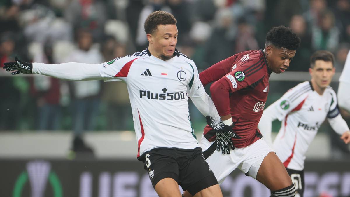 Piłkarze Legii Warszawa walczą o piłkę z zawodnikiem Sparty Praga na boisku.