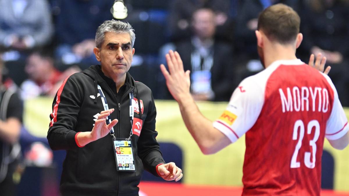 Trener wskazujący coś zawodnikowi w czerwonej koszulce z numerem 23 na plecach.