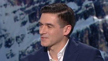 Portret mężczyzny w garniturze na tle zaśnieżonych g&oacute;r.