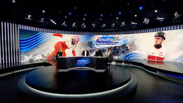 Studio telewizyjne z grafikami narciarskimi i prezenterami przy stole.