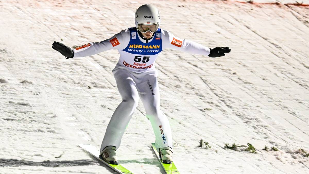 Skoczek narciarski w białym stroju z numerem 55 wykonuje skok.