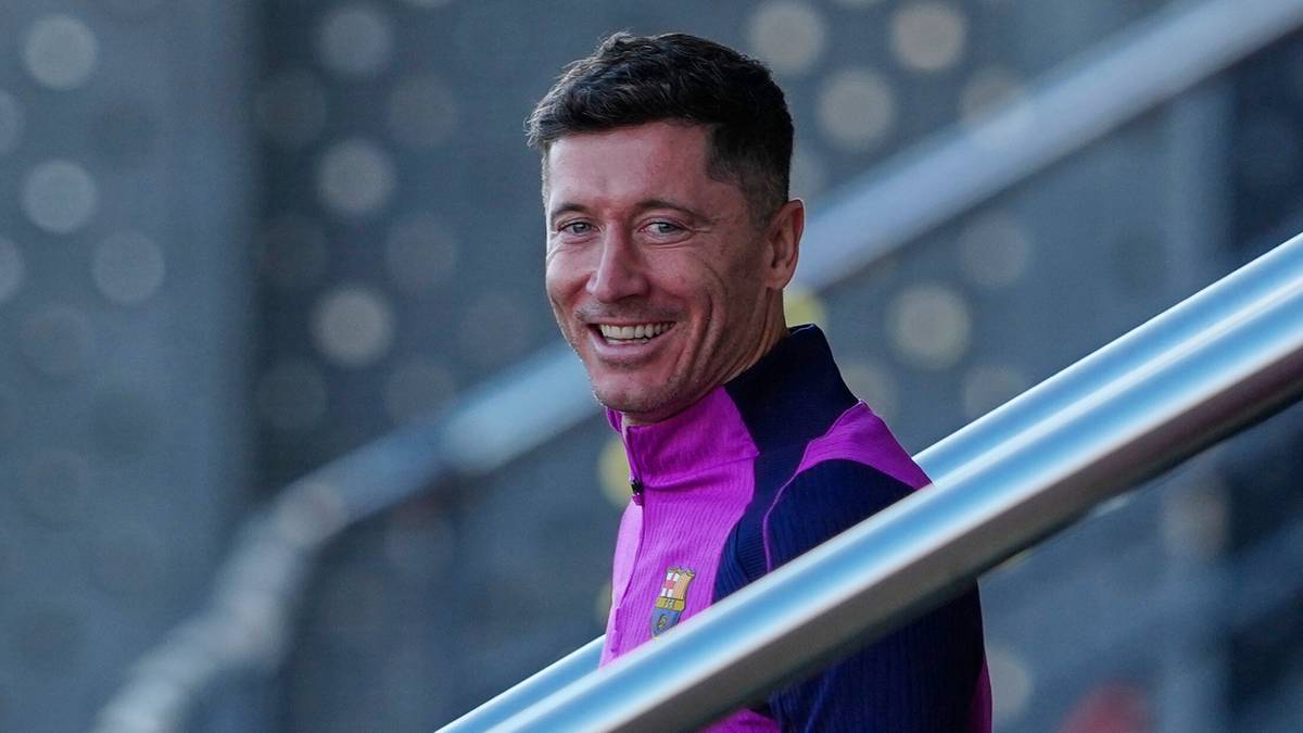 Robert Lewandowski w stroju FC Barcelony idzie po schodach i uśmiecha się.