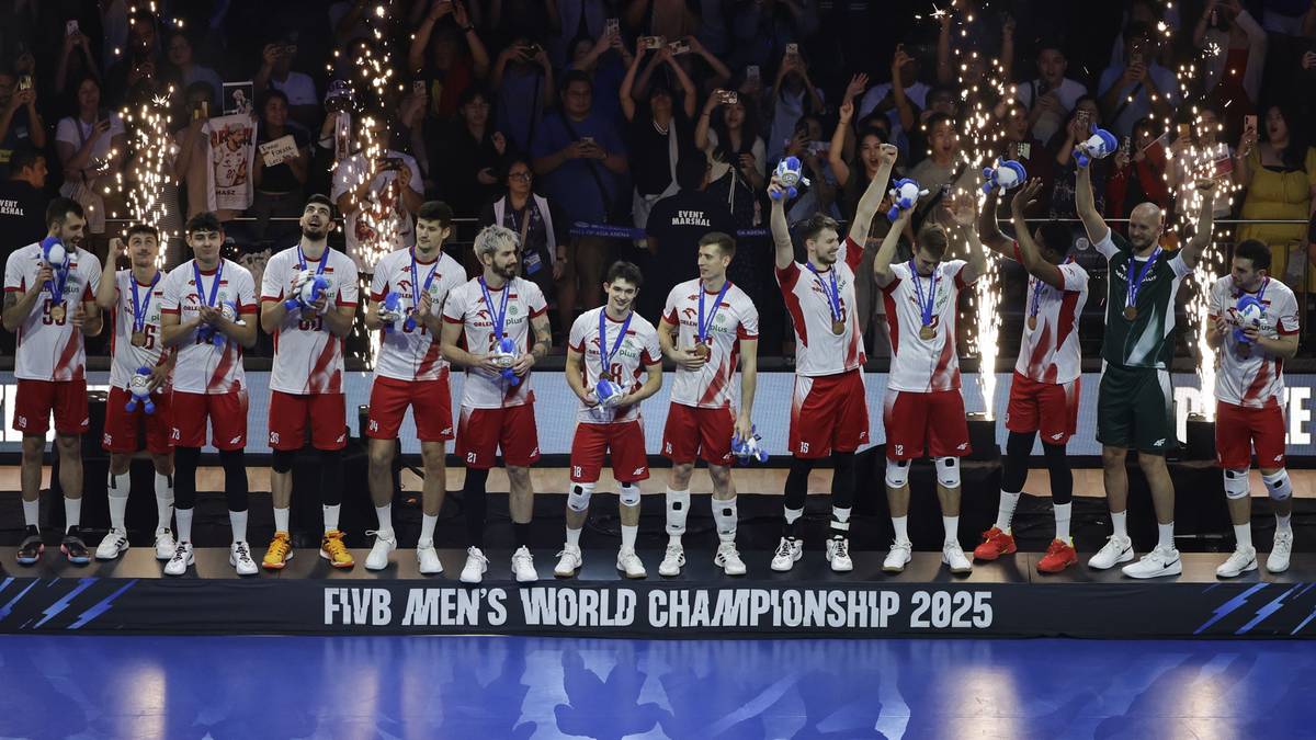 Grupa siatkarzy na podium z medalami na szyjach, niekt&oacute;rzy trzymają w g&oacute;rze piłkę lub trofeum.