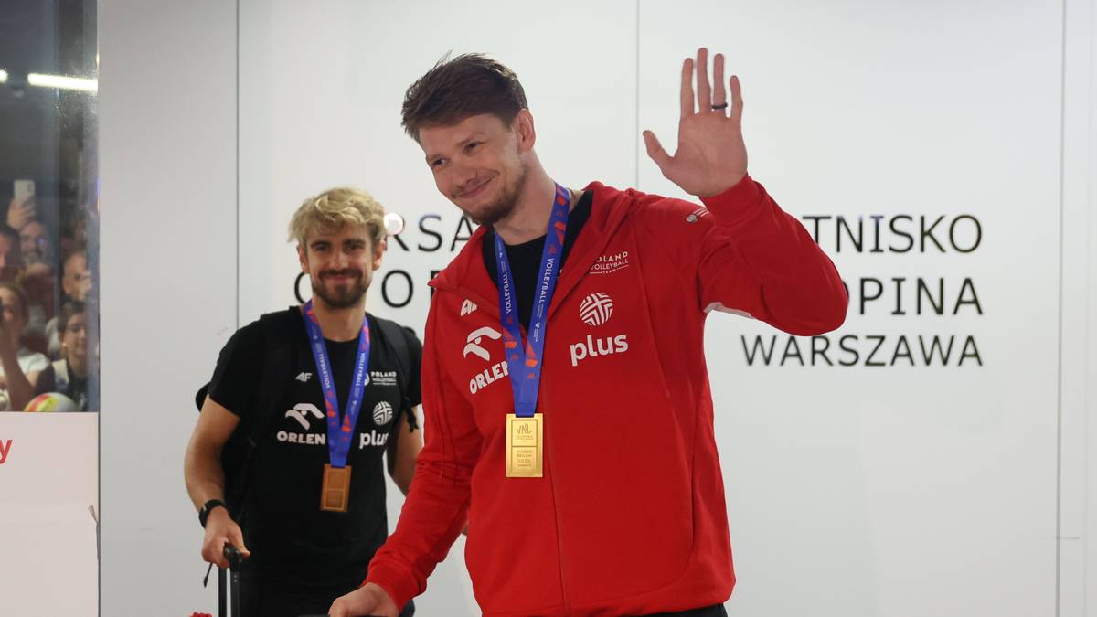 Dwóch polskich siatkarzy pozuje do zdjęcia, obaj mają na szyjach złote medale Ligi Narodów. Siatkarz na pierwszym planie w czerwonej bluzie z kapturem i okularach przeciwsłonecznych w charakterystyczny sposób faluje do widzów.