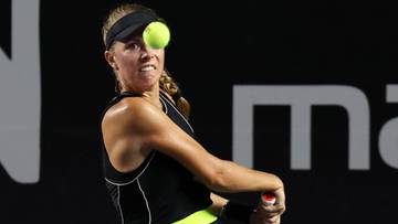 Tenisistka Magdalena Fręch w akcji podczas meczu, z piłką tenisową nad głową.