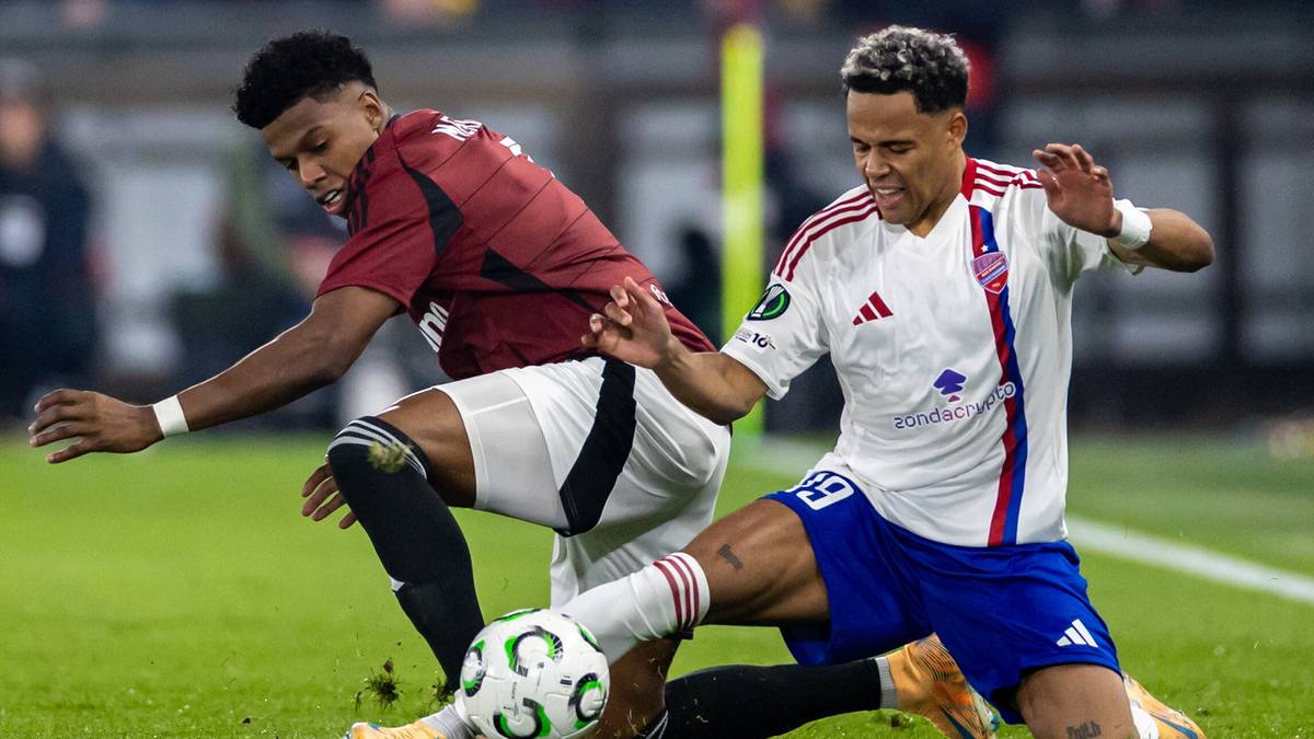 Dwóch piłkarzy walczy o piłkę na boisku.