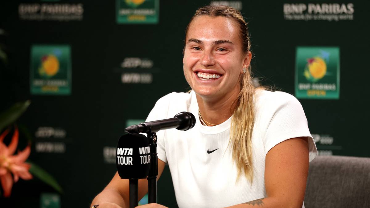 Aryna Sabalenka uśmiecha się siedząc przy mikrofonie podczas konferencji prasowej.