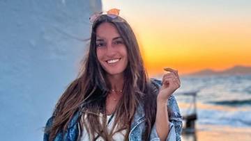 Uśmiechnięta kobieta na tle zachodzącego słońca.