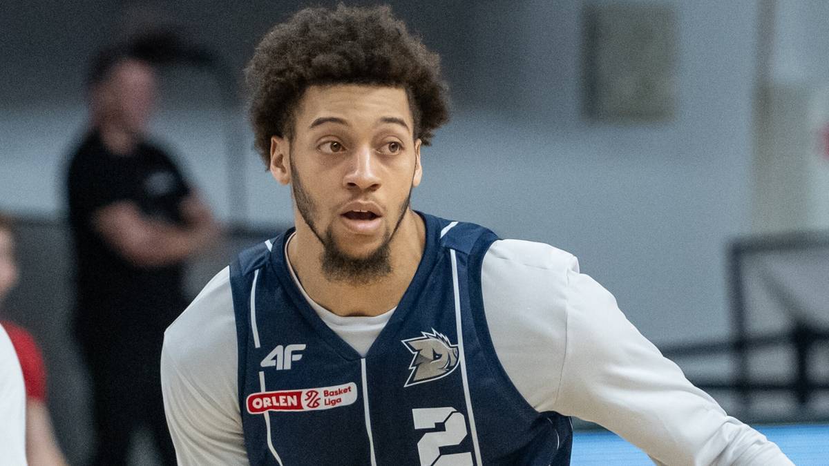 Młody koszykarz w granatowo-białej kamizelce sportowej na boisku.