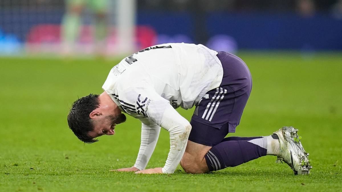 Piłkarz Manchesteru United klęczy na boisku z b&oacute;lu.