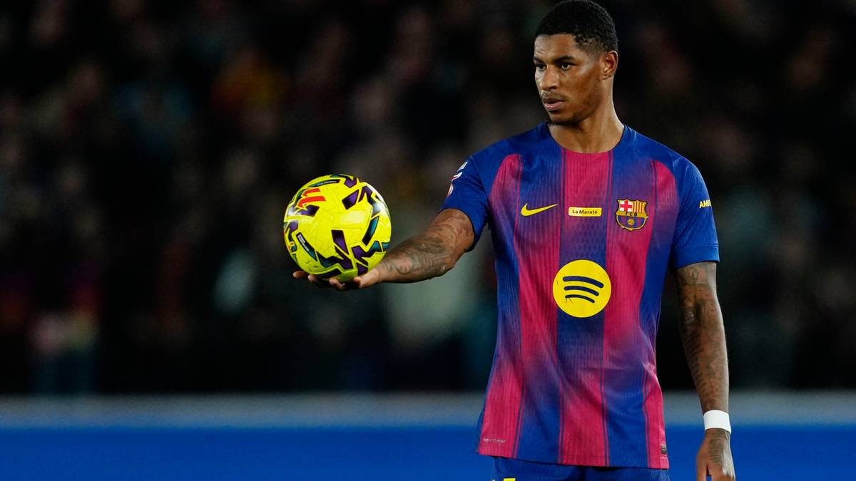 Piłkarz FC Barcelony w koszulce z numerem 14 trzyma piłkę w prawej dłoni.