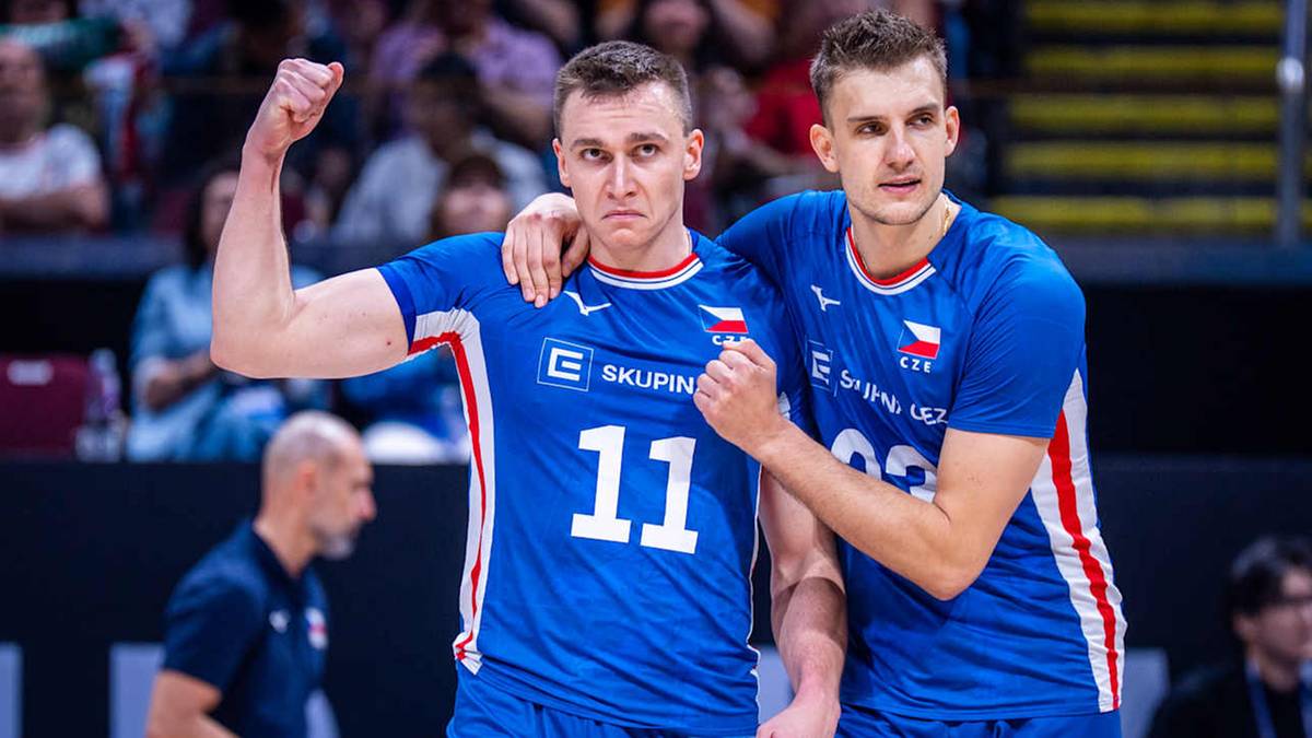 Dw&oacute;ch siatkarzy w niebieskich strojach reprezentacji Polski, jeden z nich unosi zaciśniętą pięść w geście triumfu.