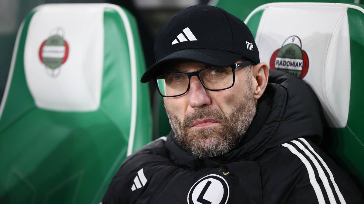 Portret trenera w okularach i czapce z daszkiem, patrzącego przed siebie z zamyśloną miną.