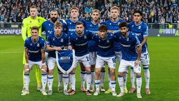 Drużyna piłkarska Lecha Poznań pozuje do zdjęcia na murawie stadionu.