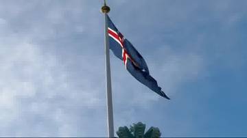 Flaga Islandii powiewająca na maszcie na tle nieba.