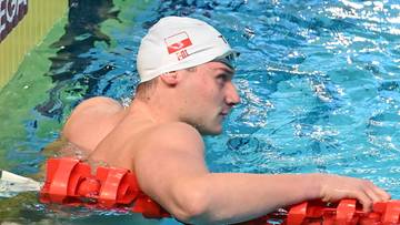 Pływak w czepku z polską flagą przy torze pływackim