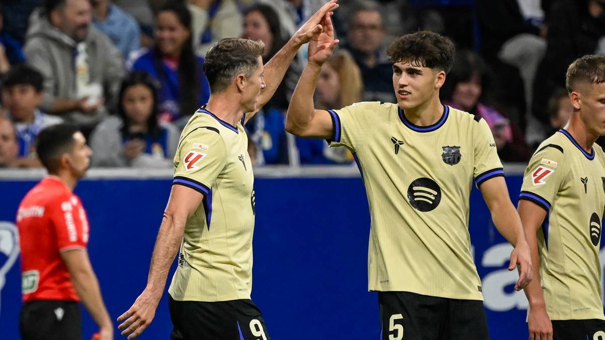 Piłkarze FC Barcelony, Robert Lewandowski i Lamine Yamal, świętują zdobycie bramki, wznosząc ręce do góry w geście radości. Obaj są ubrani w żółte koszulki z niebieskimi elementami i numerami na plecach. Lewandowski nosi numer 9, a Yamal numer 27.