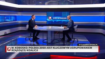 Dwóch mężczyzn siedzi przy okrągłym stole w studiu telewizyjnym, rozmawiając. Na ekranie w tle widnieje logo programu „Gość Wydarzeń”.