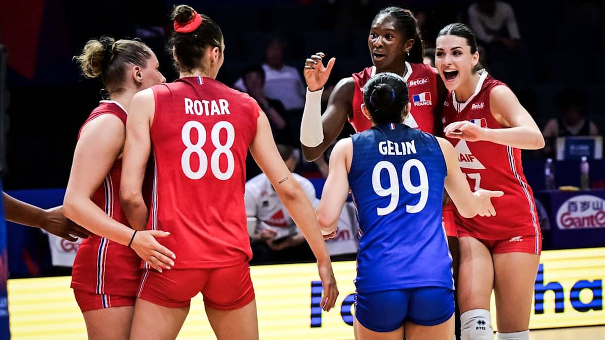 Cztery siatkarki w czerwonych strojach podczas meczu Ligi Narodów, komunikujące się między sobą. Jedna z nich, z numerem 88, odwrócona plecami, wyraża frustrację. W tle widać inne osoby.