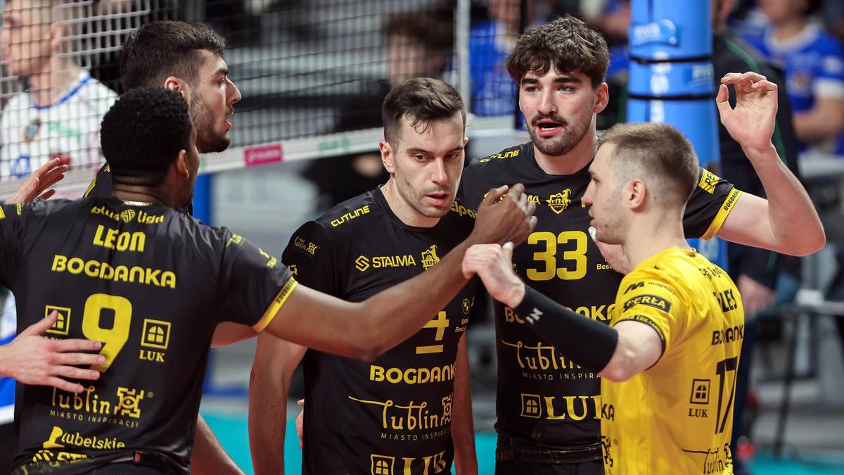 Siatkarze drużyny Bogdanka LUK Lublin w czarnych strojach z żółtymi detalami, świętujący zdobycie punktu lub omawiający strategię na boisku podczas meczu siatkówki.