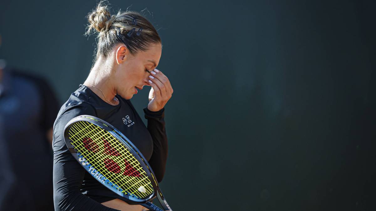 Tenisistka zamyka oczy i wyciera łzy z twarzy, trzymając rakietę.